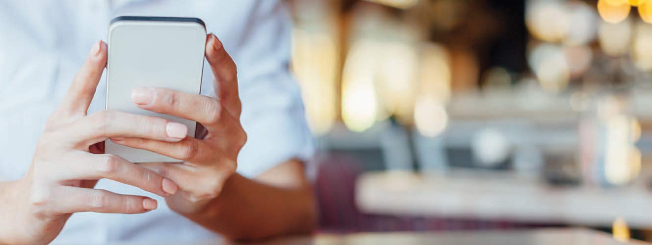 Picture of person holding a phone in the foreground while the background is blurred